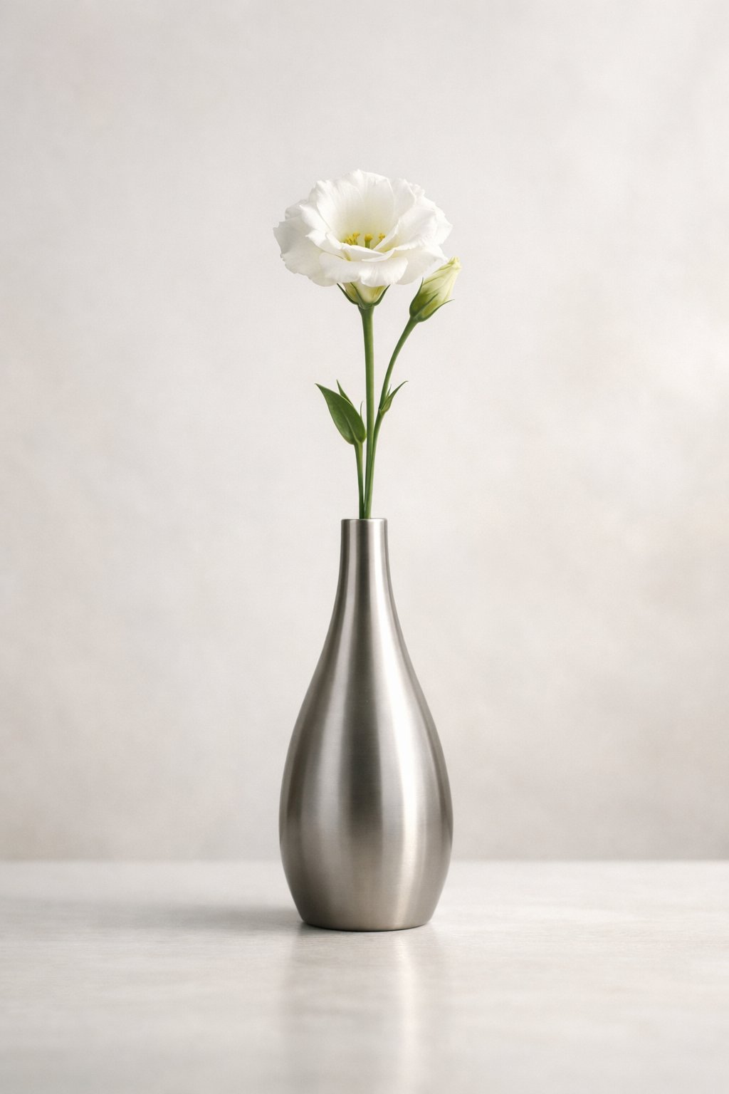 A single flower stem in a sleek vase on a light background.