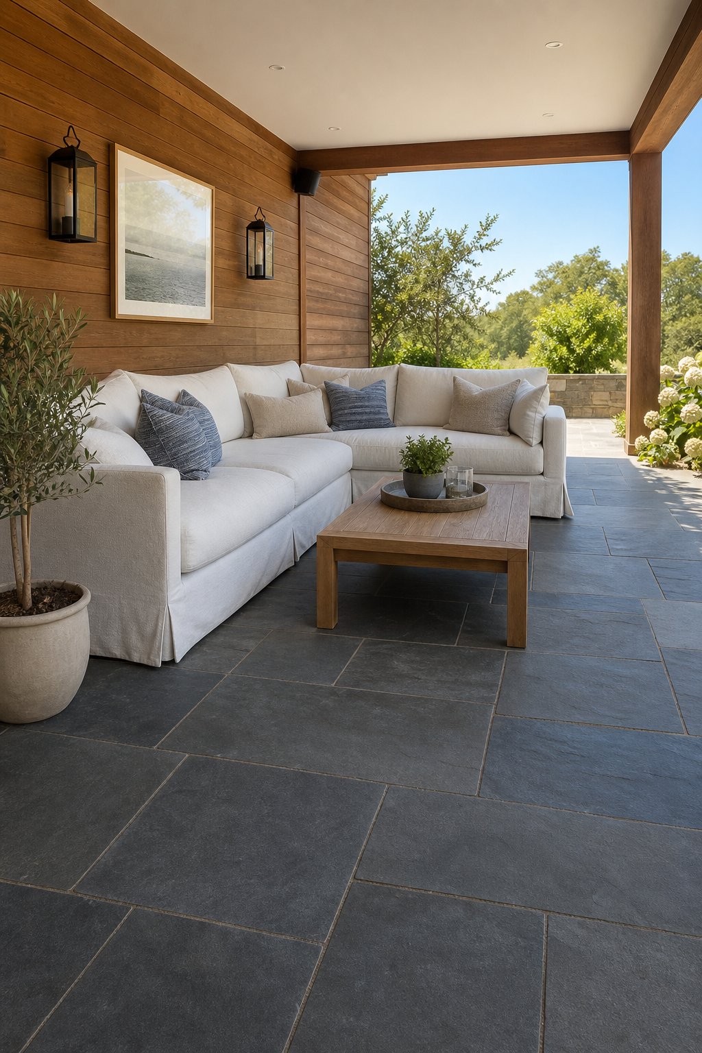 Covered patio with teak wood wall, bluestone floor, and a large slipcovered sectional sofa.